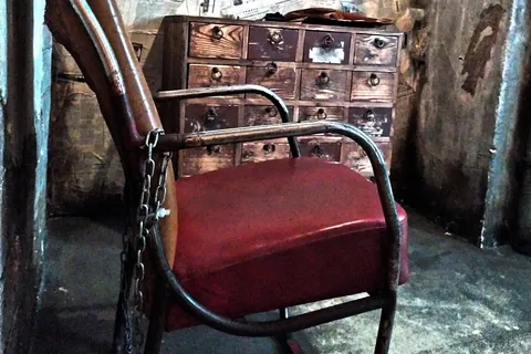 Fauteuil enchaîné devant un mur de journaux, Dernière Demeure
