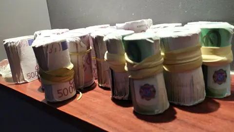 Rouleaux de billets de 500 et de 100 euros alignés sur une table