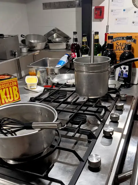 Stoves, saucepans and a box of stock in the kitchen at Magien’s