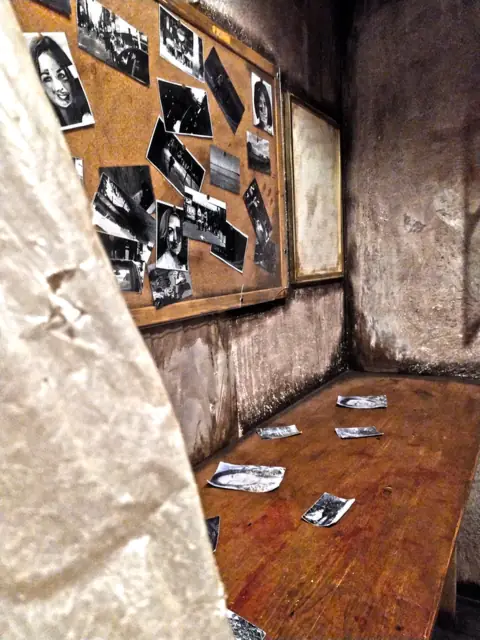 Tableau de liège couvert de photos en noir et blanc, dans le repaire du maniaque