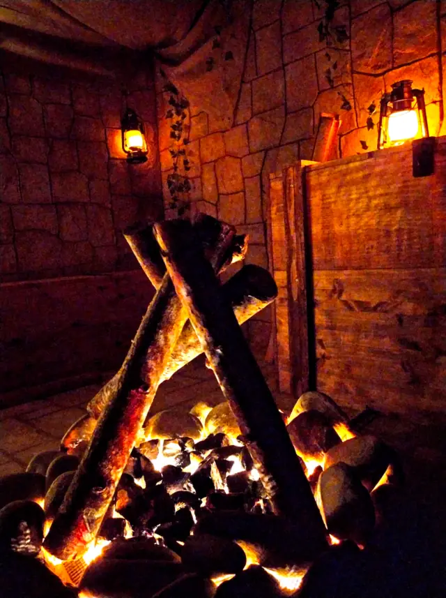 Brasier de bûches entre des caisses de bois, éclairé par des lanternes